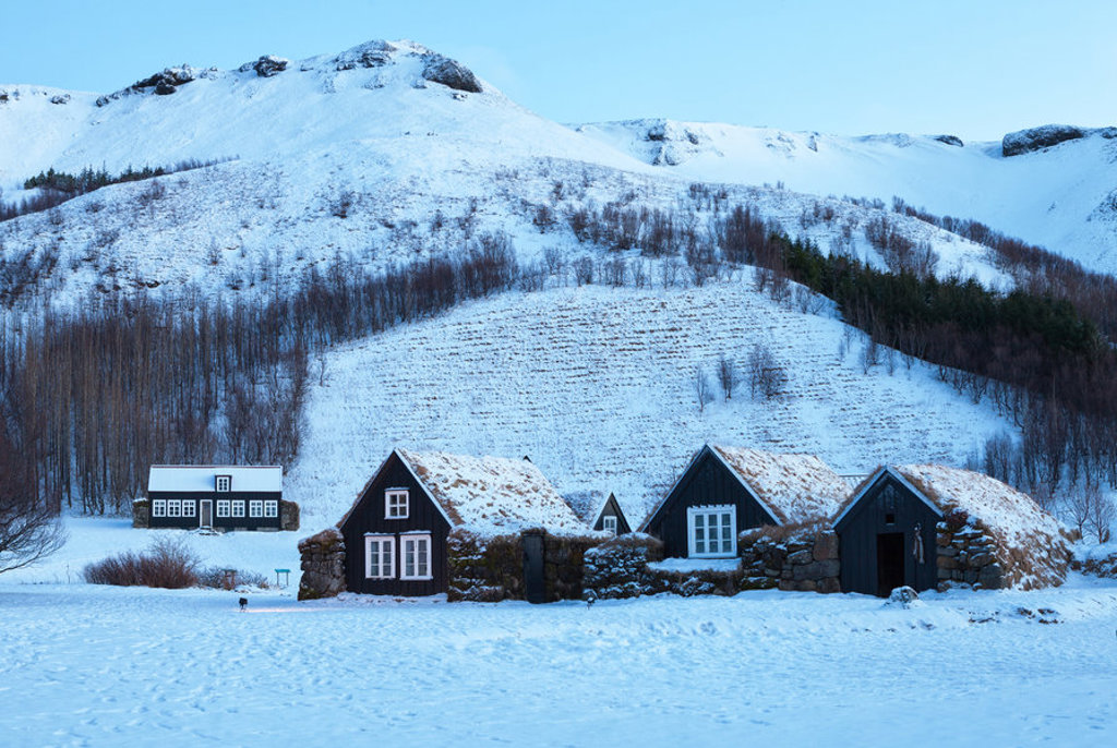 Traditionele turfhuizen in een besneeuwd landschap in IJsland tijdens een winter groepsrondreis.