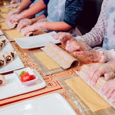 Deelnemers rollen sushi met bamboematjes tijdens een sushi workshop.