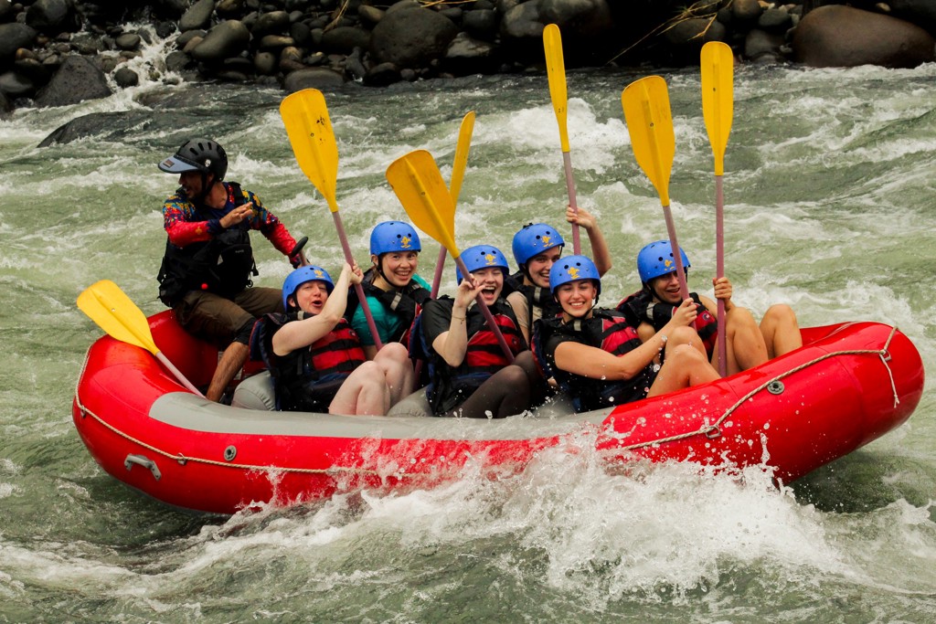 Groepsrondreis Costa Rica: deelnemers raften in een rubberboot door wildwater, met helmen en peddels.