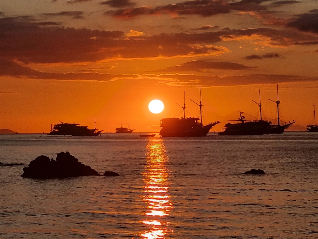 Zonsondergang boven zee met silhouetten van boten bij de Kleine Sunda Eilanden in Indonesië.
