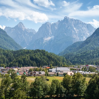 Uitzicht op een Sloveens alpendorp met groene valleien en hoge bergtoppen tijdens een 22-35ers reis Slovenië.