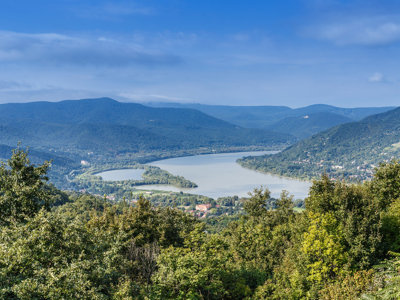Uitzicht op de Donauvallei met rivierbocht, groene heuvels en blauwe lucht tijdens een fietsreis langs de Donau.