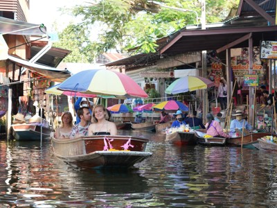 Boottocht langs de drijvende markt in Thailand met kleurrijke parasols en verkopers in smalle kanaaltjes.