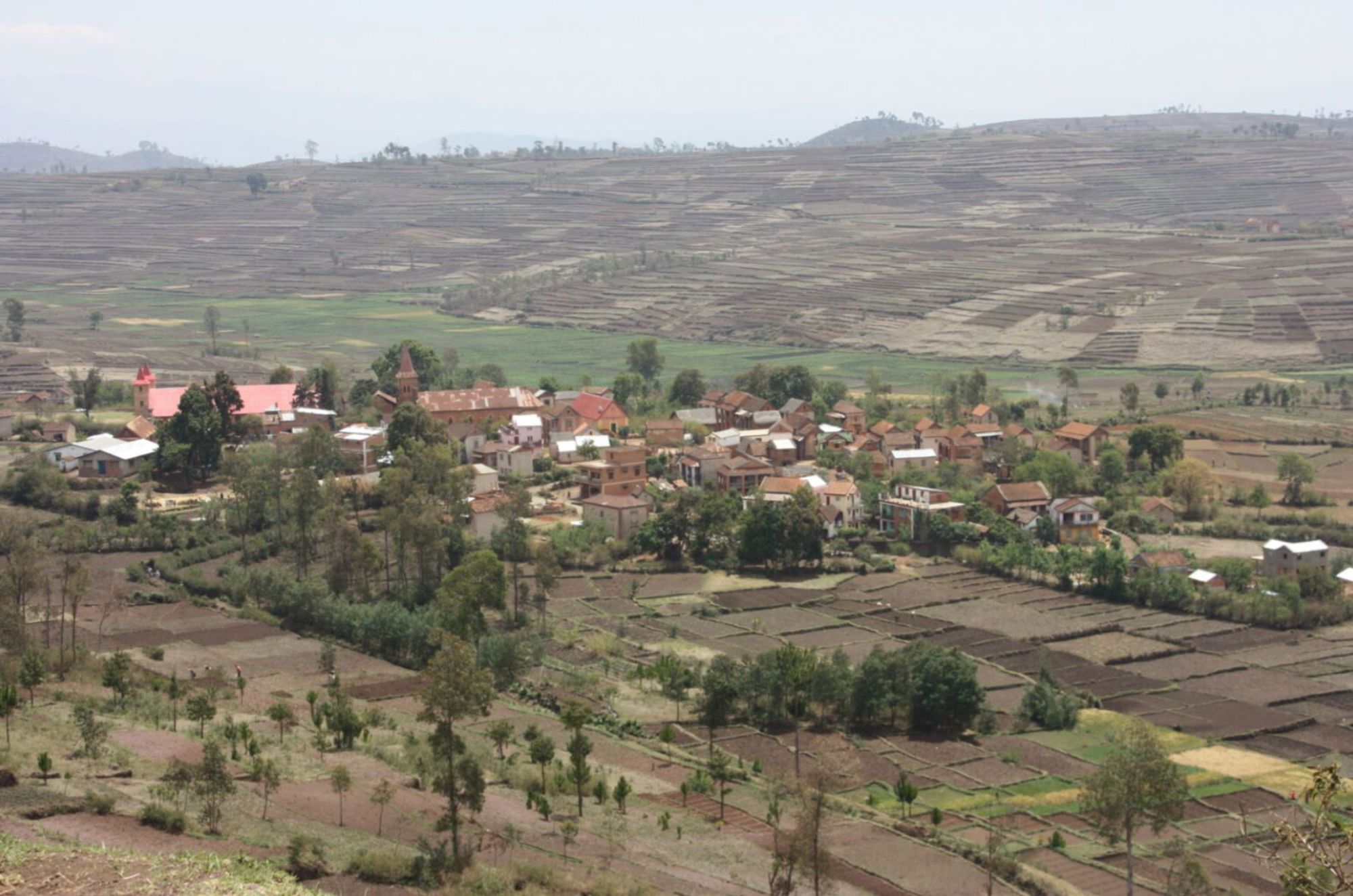 Panorama van een dorp met terrassenlandbouw en akkers in de heuvels van Madagascar.