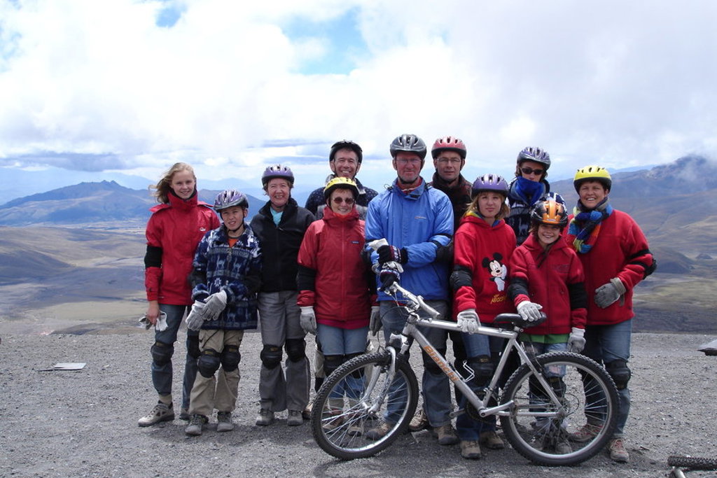 Gezin met mountainbikes en helmen op een hoogvlakte in Ecuador tijdens een familiereis, met bergen op de achtergrond.