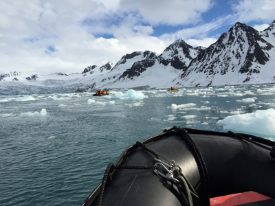 Zodiacboot vaart tussen drijvend ijs langs besneeuwde bergen op Spitsbergen.