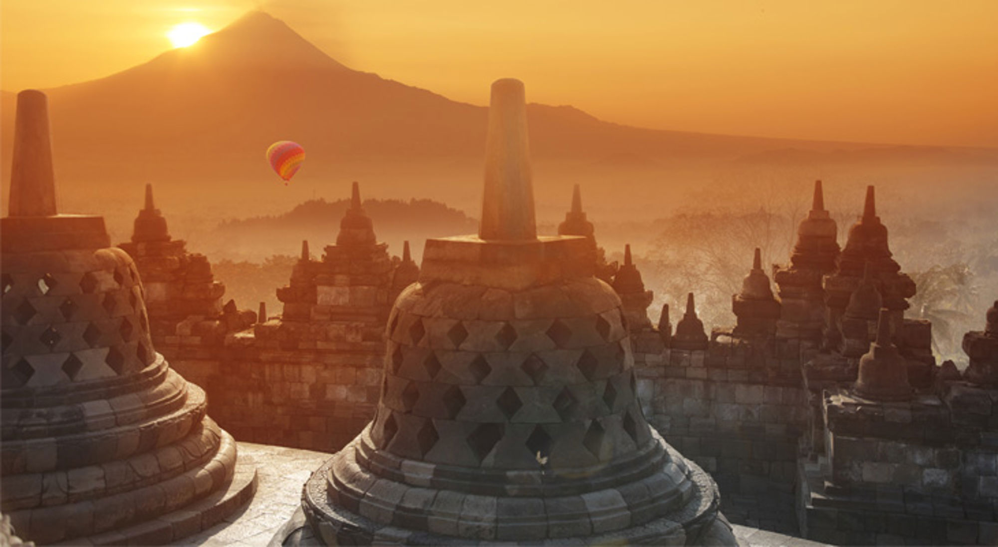 Borobodur tempel zonsondergang Indonesië Zonsopkomst bij Borobudur-tempel op Java, met een luchtballon boven het mistige landschap.