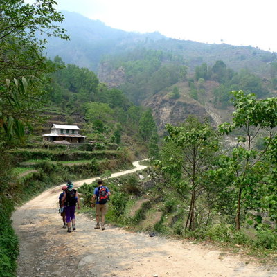 Wandelaars op een bergpad door groene heuvels tijdens een groepsrondreis in Nepal.