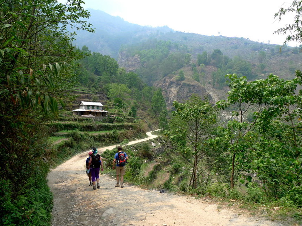 Wandelaars op een bergpad door groene heuvels tijdens een groepsrondreis in Nepal.