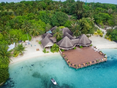 Overwaterresort met rieten daken aan wit zandstrand en turquoise lagune op de Malediven.