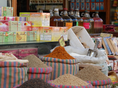 Kruiden en lokale producten op een markt in Egypte, met zakken specerijen en flessen olie op de kraam.