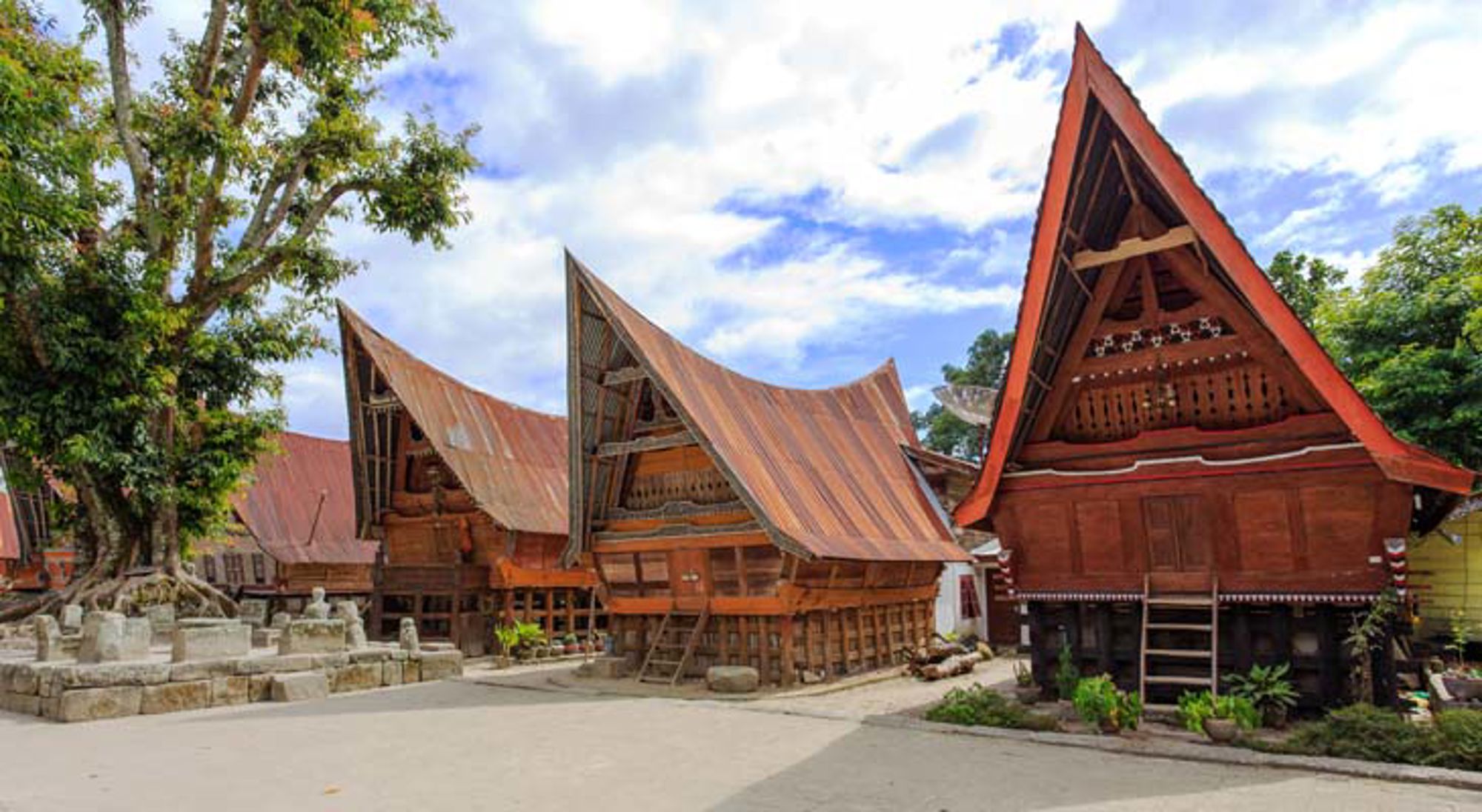 Traditionele Indonesische tempel met pagodedaken tussen palmbomen.