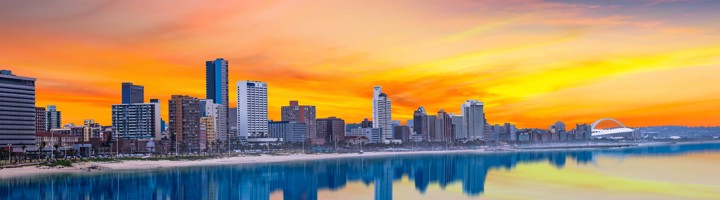 Skyline van Durban bij zonsondergang, weerspiegeld in de Indische Oceaan.