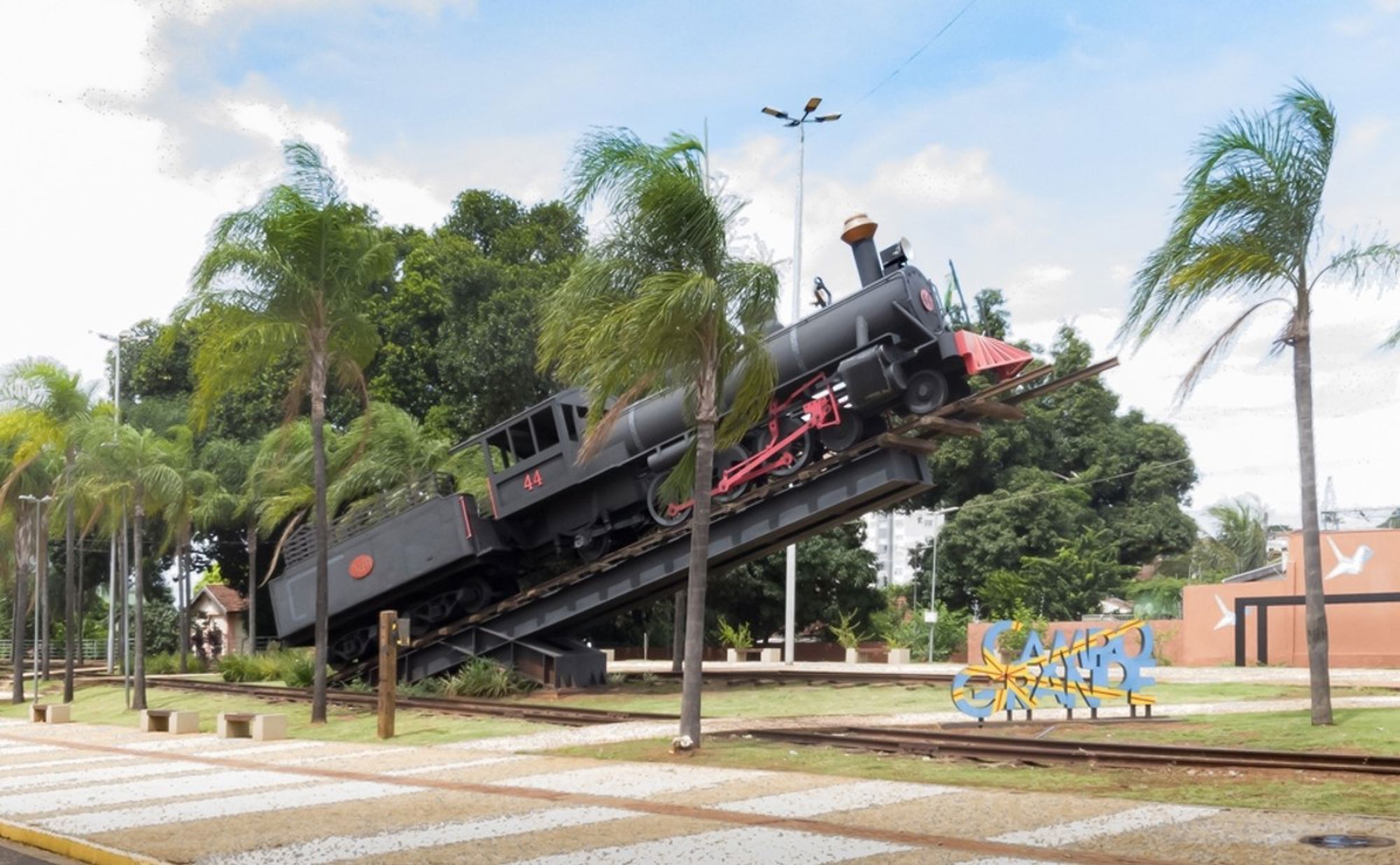 Stoomlocomotiefmonument in Campo Grande, Brazilië, op een schuin spoor tussen palmbomen.