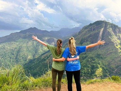 Twee reizigers met gespreide armen op een uitzichtpunt in de bergen van Sri Lanka tijdens de 15-daagse fietsreis.