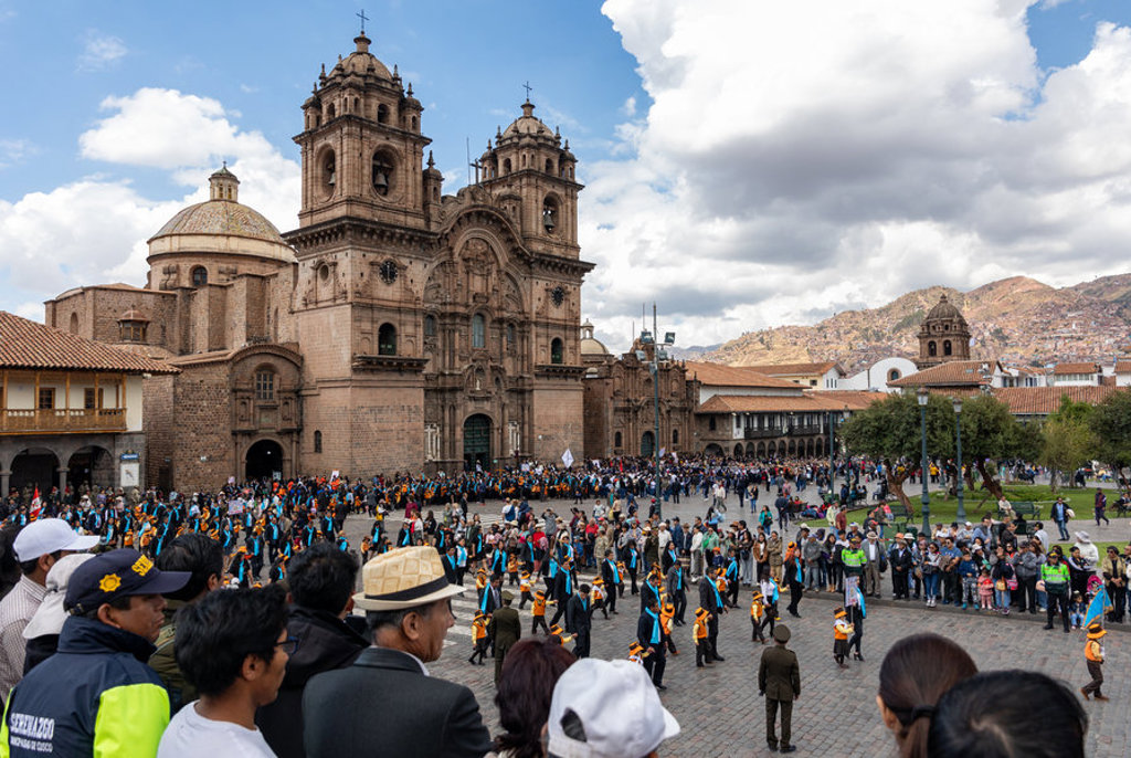 Drukke Plaza de Armas in Cusco met de kathedraal en een optocht, tijdens groepsrondreis Peru Hoogtepunten.