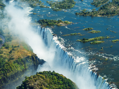 de Victoriawatervallen met nevel boven de Zambezi-rivier en groene eilandjes.