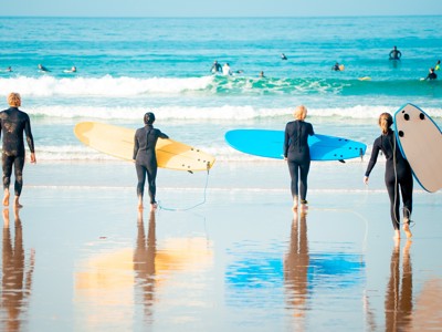 Surfers met surfboards lopen de zee in op een strand in Australië.