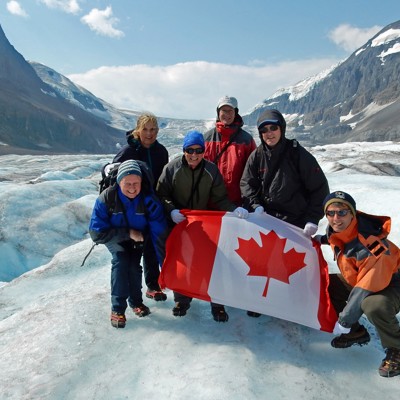 Groep reizigers met Canadese vlag op de Columbia Icefield-gletsjer tijdens Glacier Adventure-excursie.