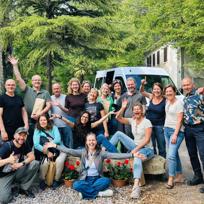 Groepsfoto van reizigers tijdens een groepsrondreis in Slovenië, bij een bus in een groene omgeving.