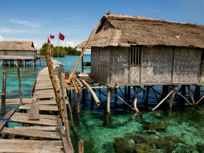 Houten hutten op palen en een steiger boven helderblauw zeewater op Sulawesi.