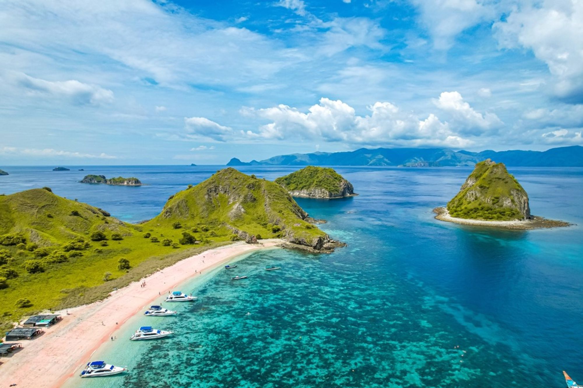 Uitzicht op Padar Island bij Komodo National Park, Indonesië, met roze strand, turquoise zee en groene heuvels.
