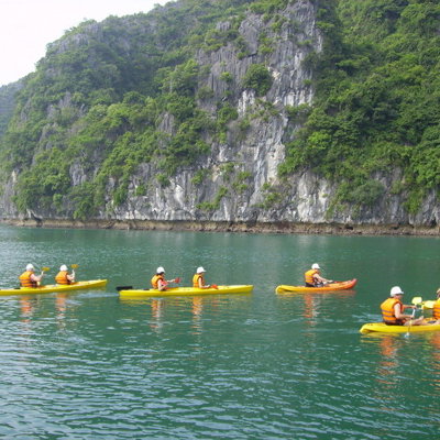 Kajakken in Halong Bay tijdens een familiereis Vietnam, met kalkstenen kliffen op de achtergrond.