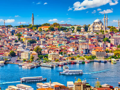 Panorama van Istanbul met de Gouden Hoorn, veerboten en de Süleymaniye-moskee onder een blauwe lucht.