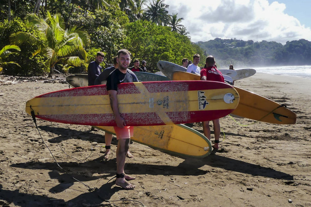 Jongeren met surfplanken op het strand tijdens een 22-35ers reis in Costa Rica.
