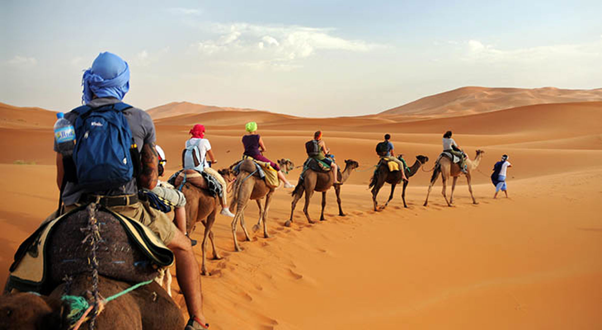 Karavaan met toeristen op kamelen door de zandduinen van de Sahara in Marokko.