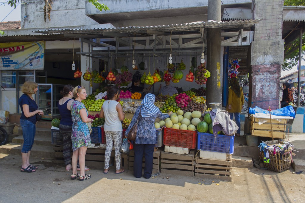 Groepsrondreis Java & Bali: reizigers bij een kleurrijke fruitkraam op een lokale markt in Indonesië.
