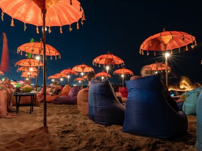 Avond op het strand van Bali met zitzakken en verlichte parasols.