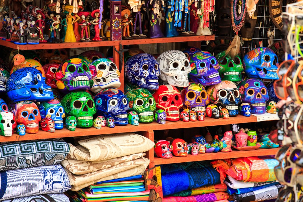 Kleurrijke Mexicaanse schedelmaskers en souvenirs op een markt, tijdens een familiereis langs Mexico hoogtepunten.