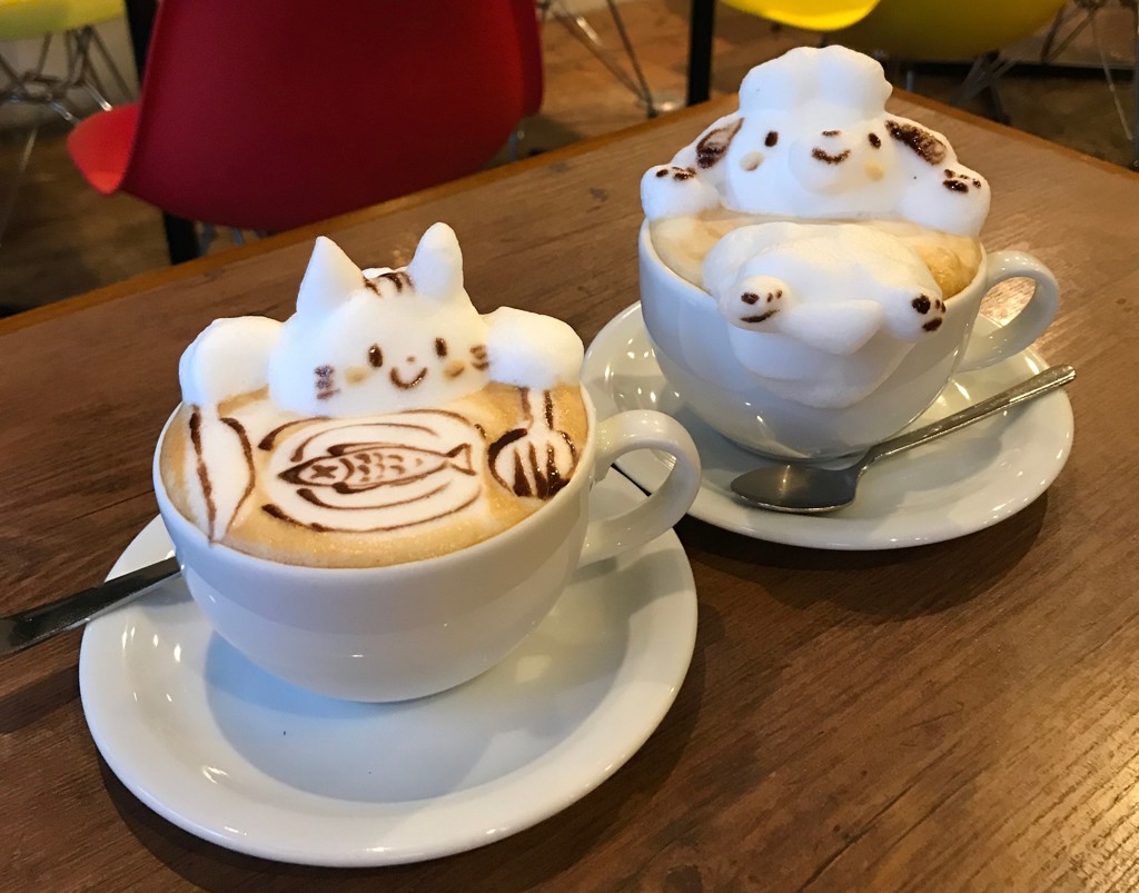 Schuimkunst in cappuccino met kattenfiguren in een café tijdens familiereis Japan.