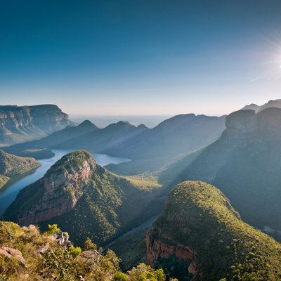 Panorama over de Blyde River Canyon in Zuid-Afrika met kronkelende rivier en bergen in de ochtendzon.