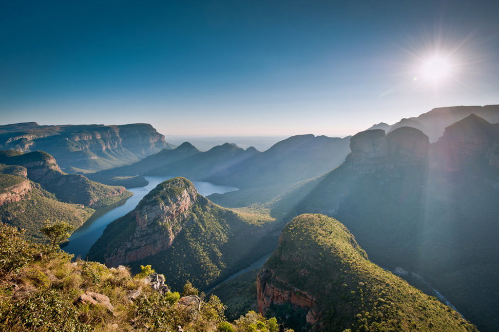 Panorama over de Blyde River Canyon in Zuid-Afrika met kronkelende rivier en bergen in de ochtendzon.
