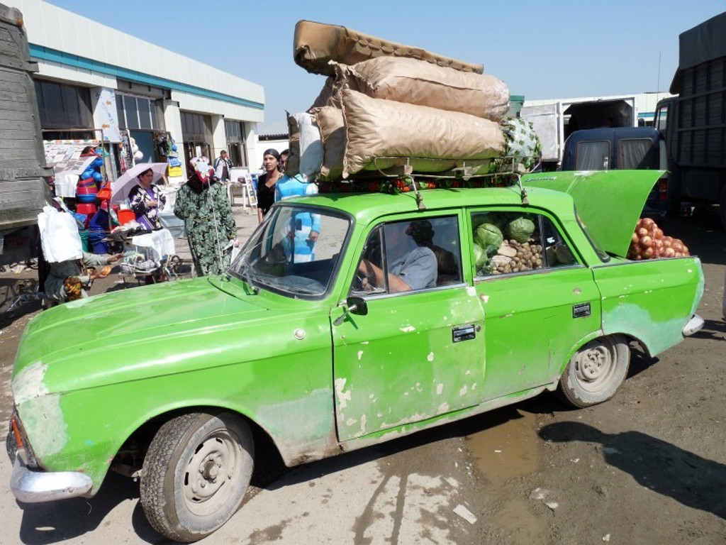 Groene auto vol groente en bagage op een markt langs de Zijderoute tijdens een groepsrondreis.
