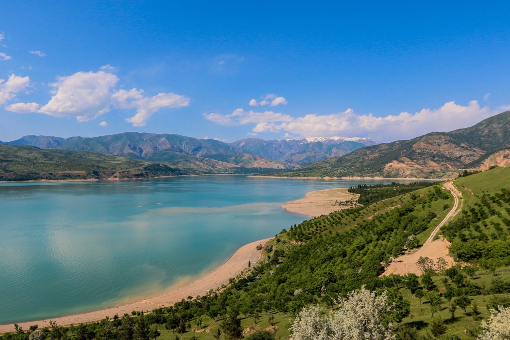 Panoramisch uitzicht op een bergmeer met groene heuvels en besneeuwde toppen in Oezbekistan.