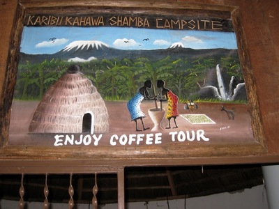 Bord bij Karibu Kahawa Shamba Campsite met “Enjoy Coffee Tour” en illustratie van koffieplanten en Kilimanjaro.