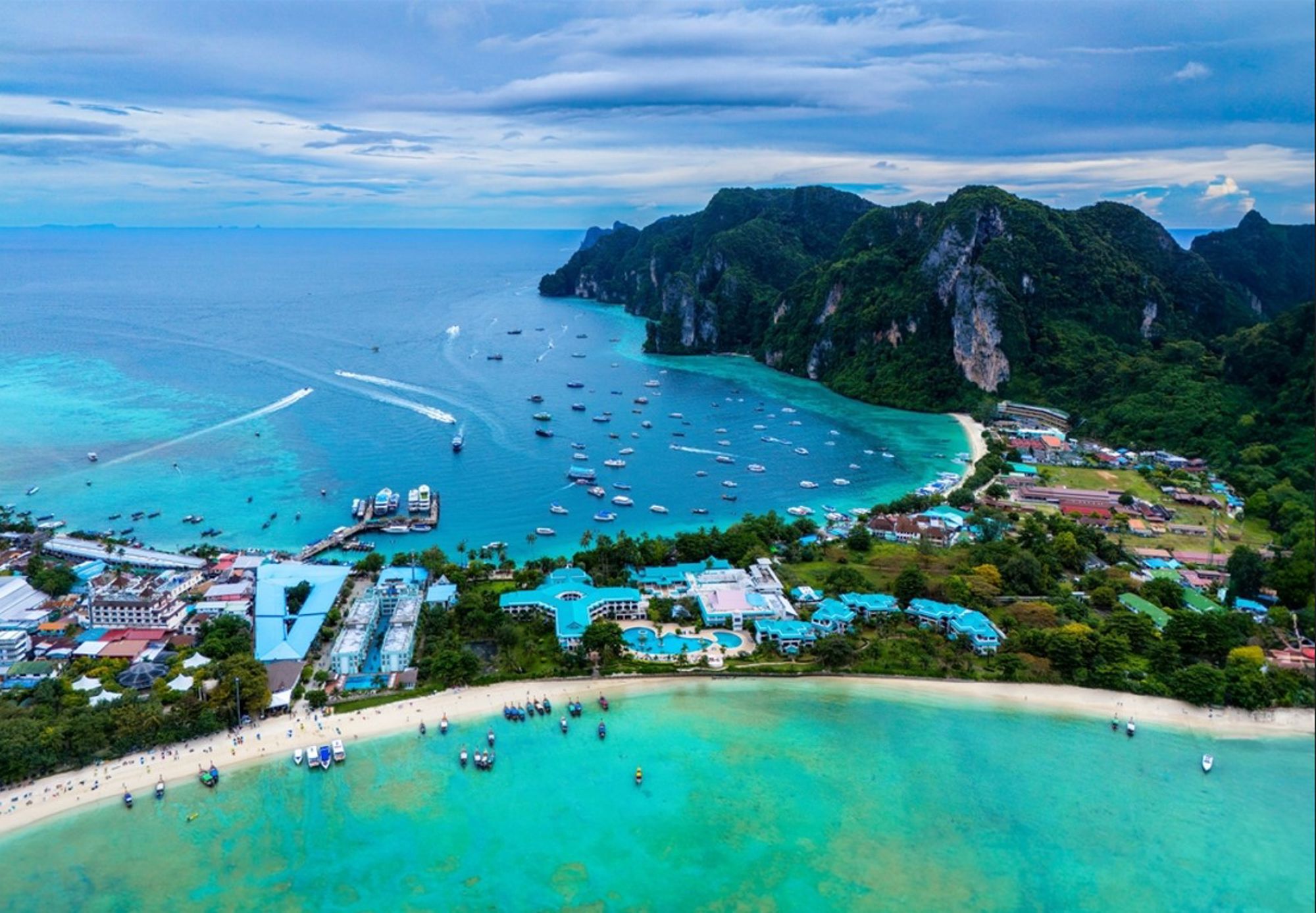 Uitzicht op Maya Bay bij Koh Phi Phi in Thailand, met turquoise zee, boten en kalkstenen kliffen.