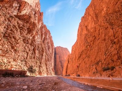 Hoge rotswanden van de Todra-kloof in Marokko langs de Route Marokko, met weg en rivierbedding.