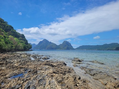 Rotsachtige kust met helderblauw water en groene eilanden in de baai van El Nido, Filipijnen.