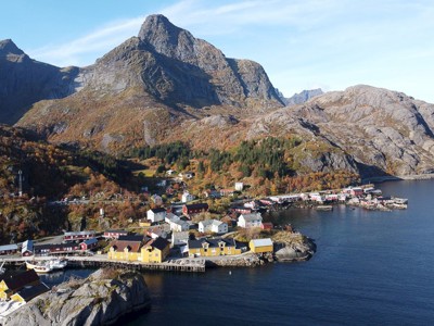 Vissersdorp aan de kust van de Lofoten in Noorwegen, met gekleurde huizen en bergen op de achtergrond.