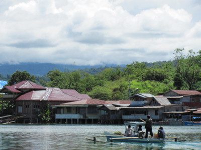 Traditionele boot vaart over het Tempe-meer langs paalwoningen en groene heuvels op Sulawesi.