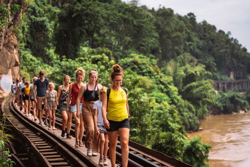 Familiereis Thailand: groep wandelt over de Death Railway langs de rivier bij Kanchanaburi.