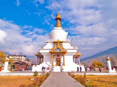 Witte chorten met gouden spits in Thimphu, Bhutan, met bergen op de achtergrond.