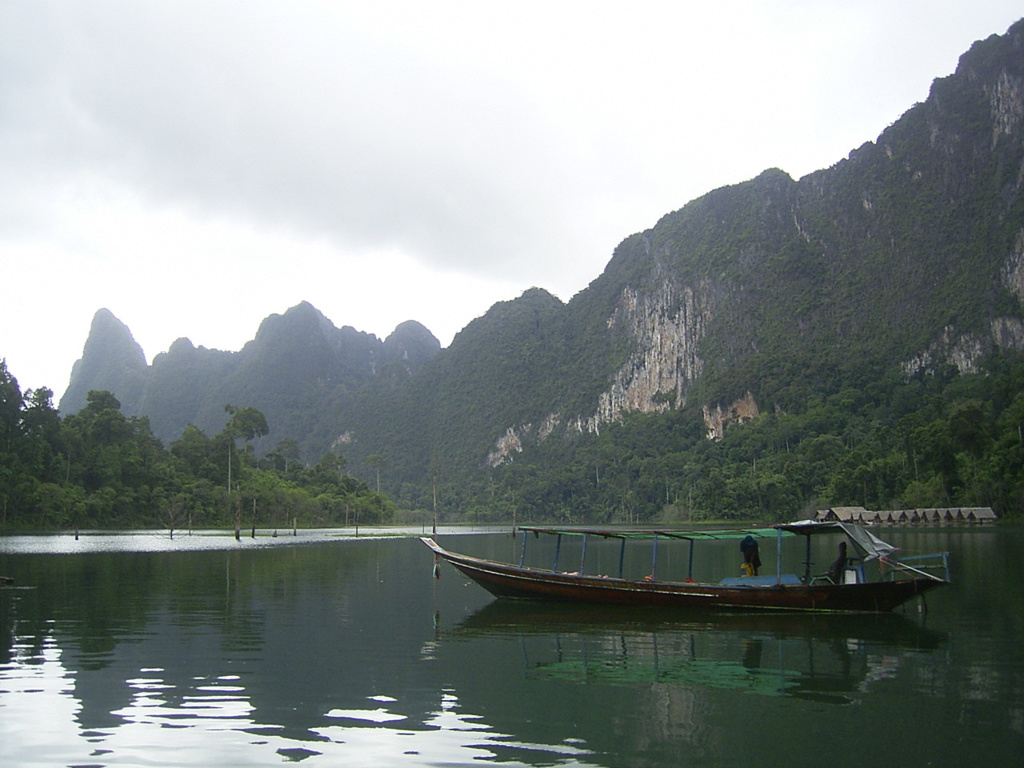 Longtailboot op een rustig meer met groene kalksteenbergen in Thailand tijdens de Familiereis Chill & Adventure.