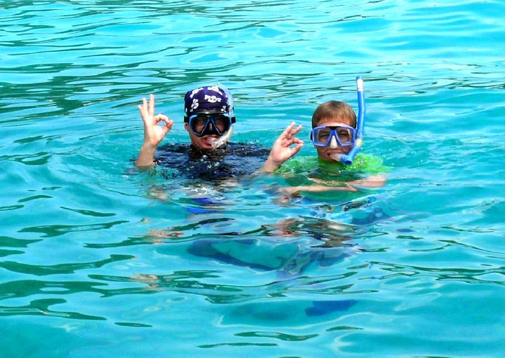 Kinderen snorkelen in helderblauw zeewater tijdens een familiereis Maleisië.