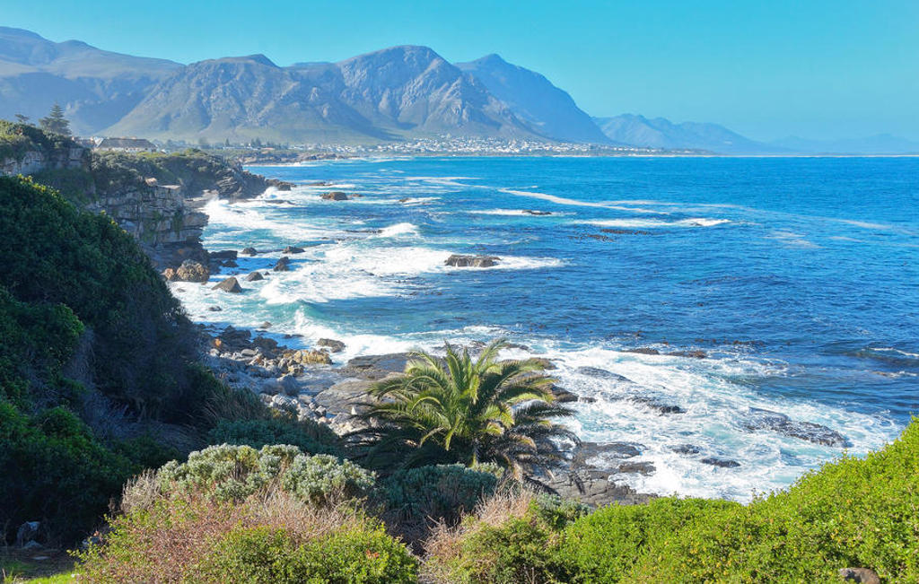 Kustlijn van Zuid-Afrika met rotsen, golven en bergen aan de horizon tijdens de premium groepsrondreis.