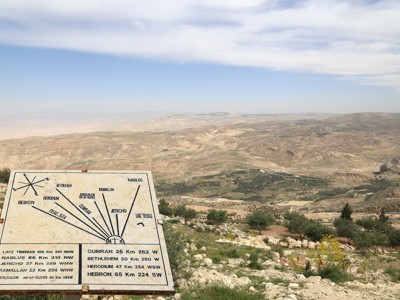 Uitzichtpunt bij Mount Nebo in Jordanië met wegwijzer en panorama over de Jordaanvallei.